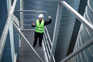 Factory worker using tablet computer in industrial factory building. In background silo storage containers. © littlewolf1989