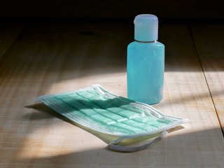 Blue alcohol sanitzer gel and mask on wooden  background. Mask and hand sanitzer gel for protection coronavirus or covid-19.