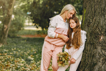 Family in a summer park. Mother in a pink suit. Little girl walking in a park.