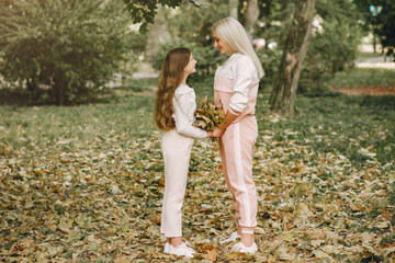 Family in a summer park. Mother in a pink suit. Little girl walking in a park.