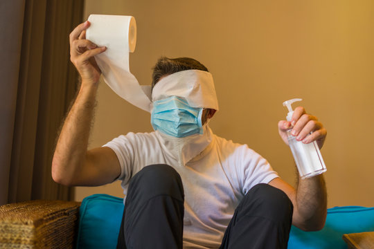 toilet paper sold out paranoia during covid-19 quarantine - crazy man in protective mask in home lockdown with head wrapped in tissue paper roll during coronavirus