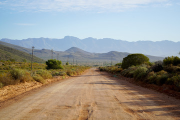Fototapeta na wymiar Long open dirt road in mountain landscape