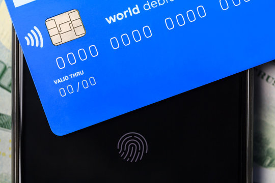 Contactless NFC system. On a smartphone with a fingerprint there is a credit card with a chip and contactless payment function.