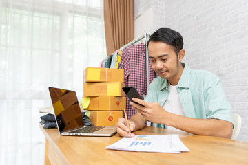 Asian man using smart phone working at home office, Selling online start up small business owner e-commerce idea concept