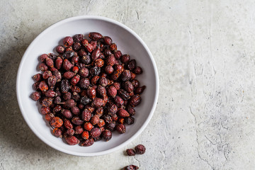 Dried rosehip berries in a white bowl, top view.