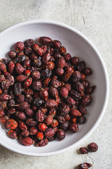 Dried rosehip berries in a white bowl, top view.
