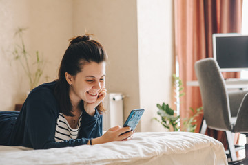 smiling woman on bed with cellphone