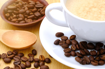 Coffee cup and beans on wooden kitchen table. Top view with morning sunlight