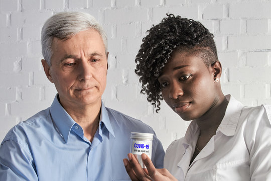 Caucasian senior team leader and African medics working in test laboratory discussing new antibody test for antibodies against novel corona virus causing COVID-19 pneumonia in heavy cases.