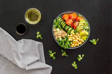 Veggie bowl. Vegetable salad with quinoa, avocado, tomato, spinach and chickpeas - on black table. Top view