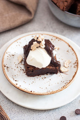 Homemade brownie with scoop of vanilla ice cream, chocolate sauce and nuts. Gray background