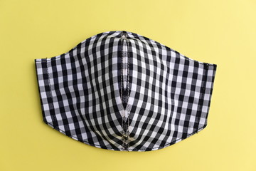 black fashion mask handmade from fabric cloth on yellow background