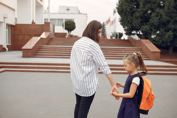 Mother and daughter. Family standing near school. Mom accompanies her child to school