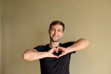 Love emotion smiling cute lovely man making heart shape hands. Place for text