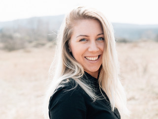 Young blonde woman smiling outdoor at summer day