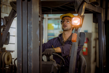 Fototapeta na wymiar Portrait worker industry factory wear safety uniform factory drive a forklift car and open car light to control production work in factory area for another worker.