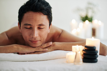 Smiling mature man resting after spa masage and enjoying atmophere of spa salon and tasty smell of...