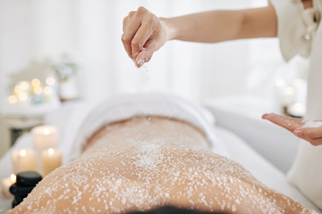 Beautician applying sea salt scrub on back of male client
