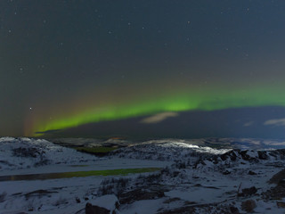 Aurora and stars in the sky .The rocks and ground are covered with snow.Frozen lake.