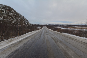 The dirt road is covered with ice .The sky is covered with clouds.