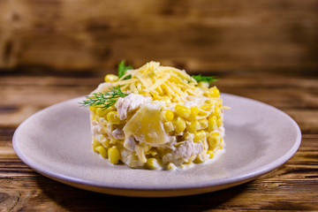 Festive salad with chicken breast, canned pineapple, cheese, sweet corn and mayonnaise on wooden table
