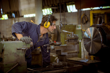 The Industry worker wearing safety uniform used lubricant oil control operating lathe grinding...