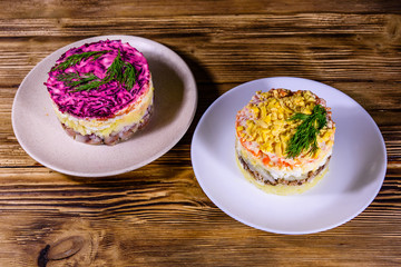 Traditional russian new year layered salads Mimosa and Herring under a fur coat (shuba) on wooden table