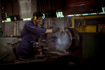 Fototapeta na wymiar The Industry worker wearing safety uniform used lubricant oil control operating lathe grinding machine working in industry factory.