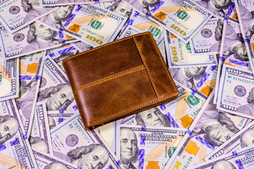 Closed brown leather wallet on the one hundred dollar banknotes