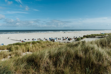 Fototapeta na wymiar Wide beach landscape with colorful beach chairs on a sunny day at the beach of Juist, Germany