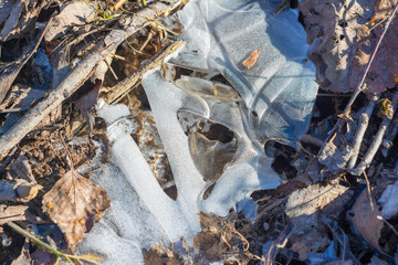Frozen footprint of the sole of the shoe against the background of dried leaves