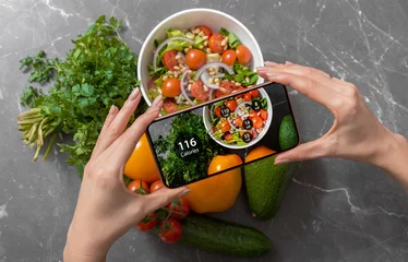 Foto op Plexiglas Vrouw gebruikt een dieet-app op een smartphone om voedingsfeiten en calorieën in haar eten bij te houden © Kaspars Grinvalds