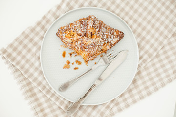 Delicious almond croissant with breadcrumbs on plate with fork and knife. Background of linen towel. 