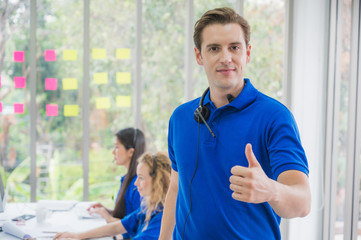 Fototapeta premium Customer support operator at work. Team Business and Delivery call center in office. Working with a headset in blue uniform while showing thumbs up.