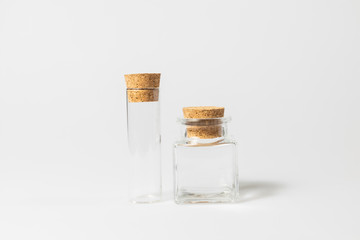 front view of transparent empty glass jar or test tube bottles with closed brown cork cap lids on white background