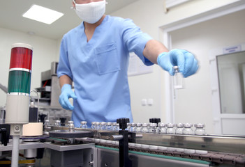 Pharmaceutical production line. The specialist controls the manufacture of ampoules