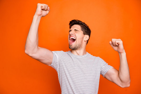 Photo of crazy funky guy yelling loud open mouth best feelings raise fists eyes closed cheerleader rejoicing wear casual striped t-shirt isolated bright orange color background