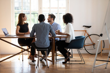 In board room gather multiethnic corporate staff communicating during morning briefing. Businesspeople planning, solving current issues. Negotiation between client and company managers process concept
