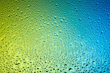 Yellow and blue water drops on glass. Background.