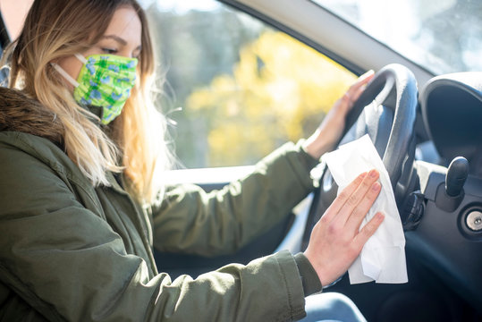 junge Frau desinfiziert Lenkrad im Auto