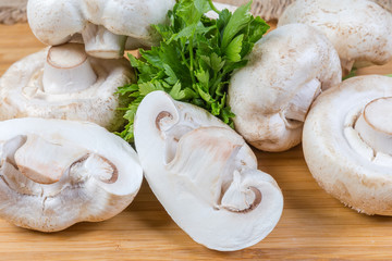 Background of uncooked button mushrooms and parsley on wooden surface