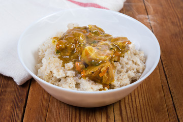 Bowl of hot barley porridge with meat sauce close-up