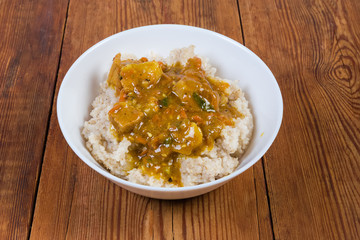 Barley porridge with meat sauce in bowl on rustic table