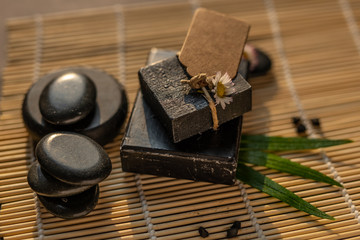 charcoal coal carbon black soap bar on a raw wood bamboo background lava stone spa skin care hygiene concept 