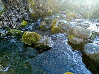 a stream flows over covered with moss stones