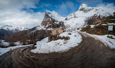 A panorama shot of a curve in the mountain with snow