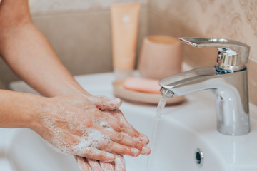 Woman use soap and washing hands under the water tap. Hygiene concept hand detail.