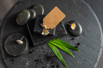 black carbon coal charcoal block soap bar on black stone with lava stones bamboo and tag room for text  spa salon concept 