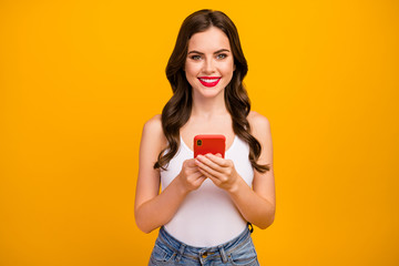 Photo of attractive lady hold telephone hands read watch new popular blog post video information interesting wear white tank-top jeans isolated bright yellow color background