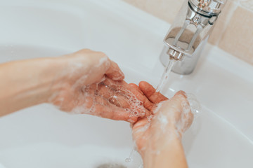 Woman use soap and washing hands under the water tap. Hygiene concept hand detail.